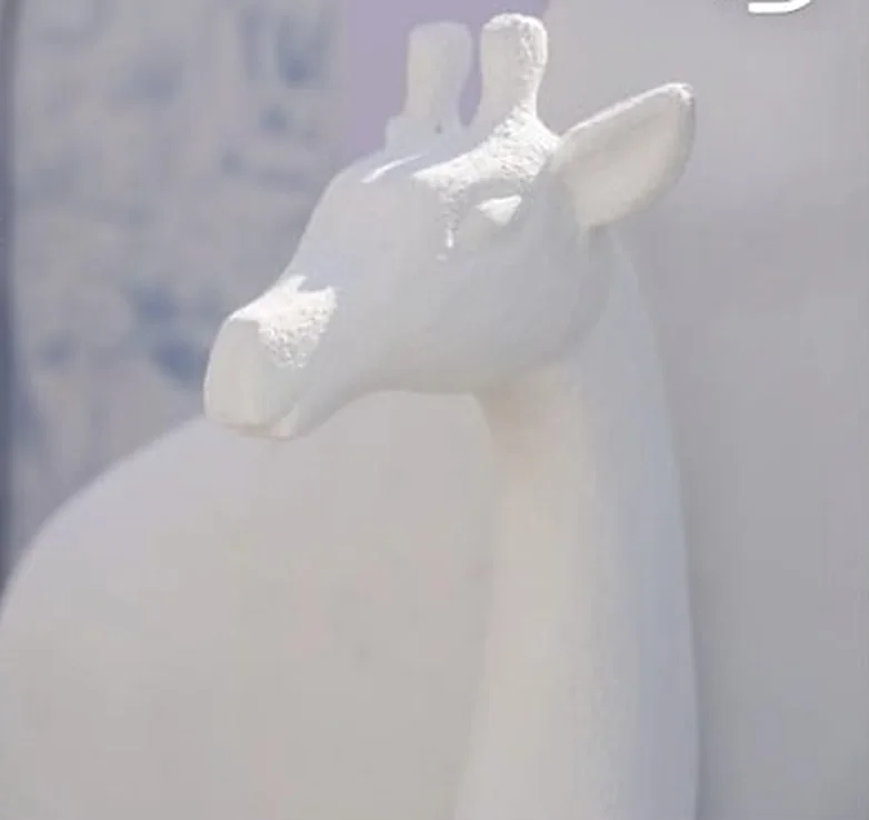 Weiße Giraffenskulptur vor Toile-Hintergrund