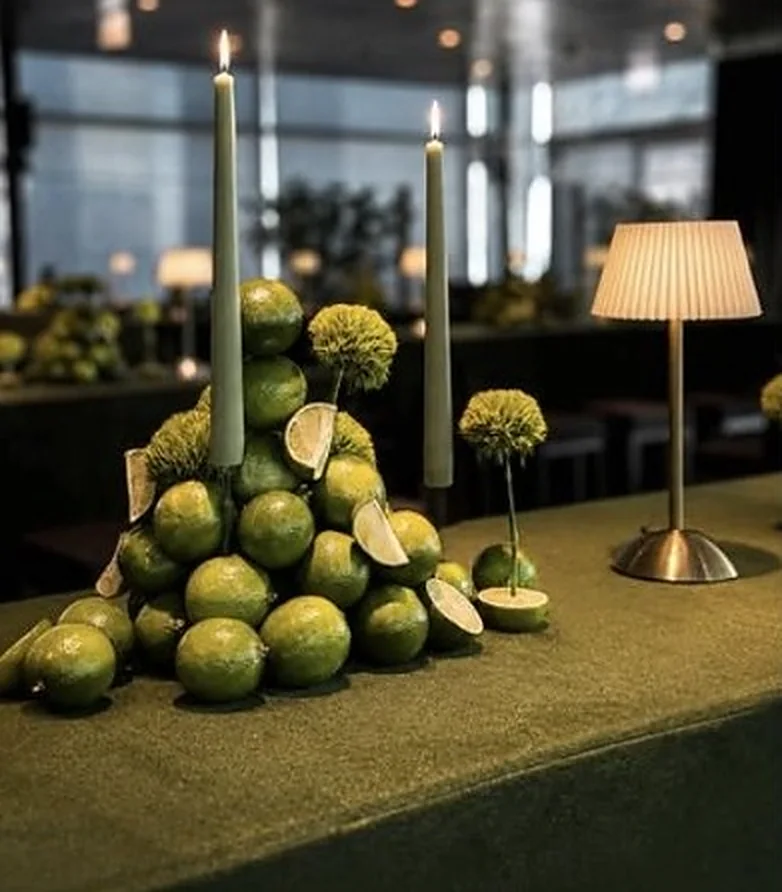 Tafel in Samtgrün mit Limettenpyramide, Kerzen und plissierter Tischlampe