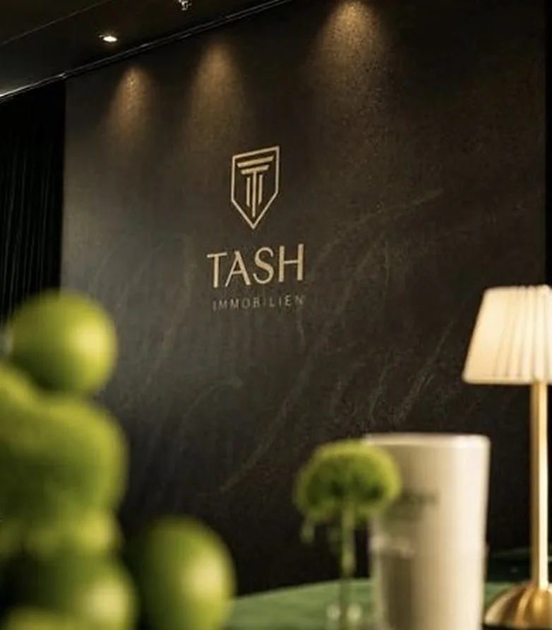 Beleuchtete Logo-Wand von TASH Immobilien