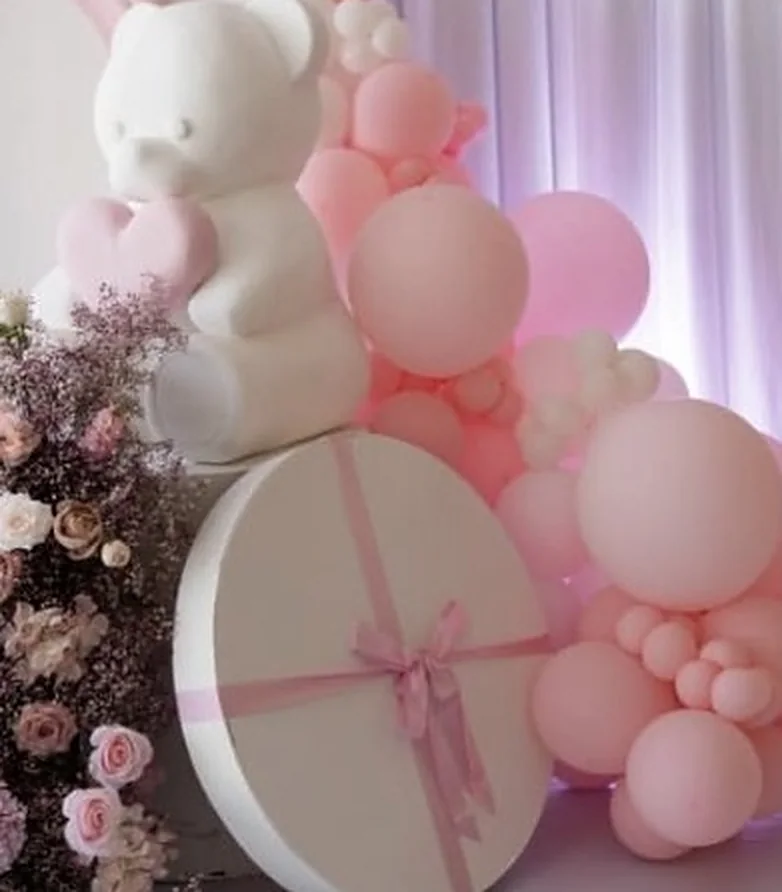 Teddybär-Skulptur mit rosa Ballons und Geschenkbox